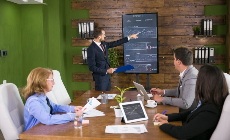 Businessman in suit having a presentation with charts on tv screen