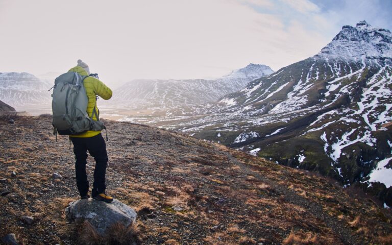 Male wearing a yellow jacket and a backpack while taking a picture of the beautiful scenery